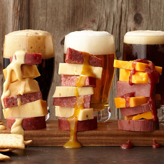 An image of Hickory Farms summer sausage, cheese, and mustard stacked in front of glasses of beer