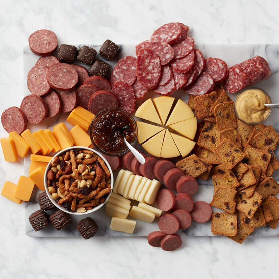 charcuterie spread featuring summer sausage, cheese, mustards, crackers, nuts, and chocolates 