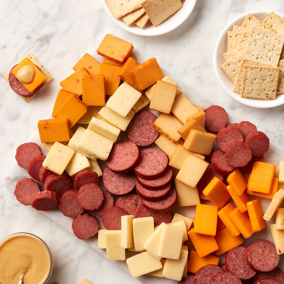 Hearty Party Gift Box meat and cheeses sliced and arranged on board with mustard and crackers