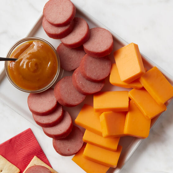 Alternate view of Hickory Farms farmhouse cheddar cheese on a meat and cheese board with turkey summer sausage and honey pineapple mustard